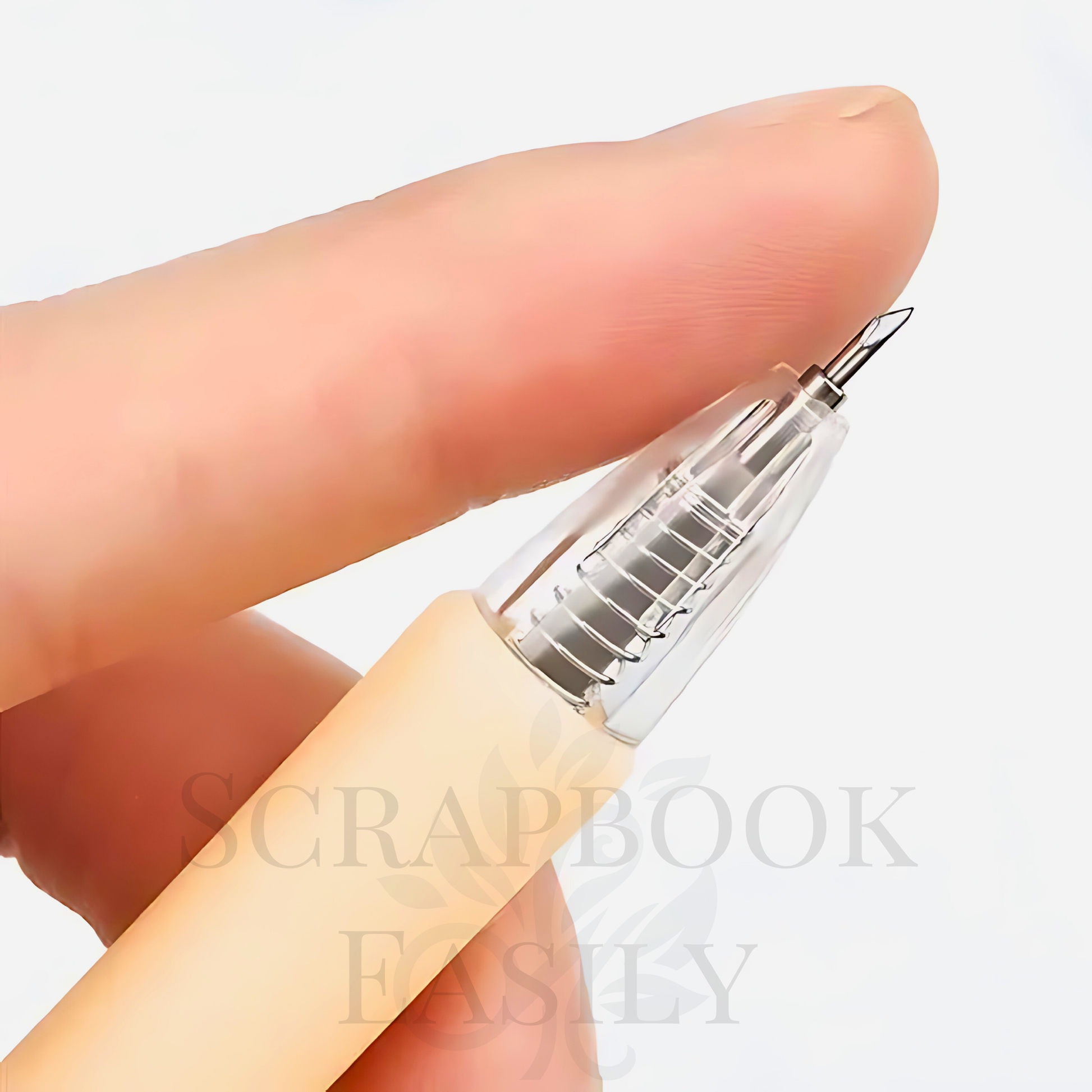 Extreme close-up of a precision craft knife pen in sunbeam golden peach, held between fingers, showcasing the retractable fine blade for accurate cutting, essential for detailed work in scrapbooking & creative crafting projects, available for online purchase.